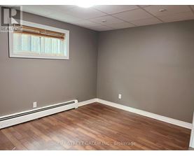 A room with wooden flooring and a window with blinds.