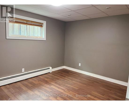 A room with wooden flooring and a window with blinds.