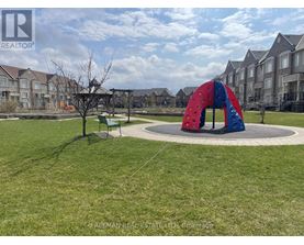 A playground with a red and blue slide in the middle of a grassy area.