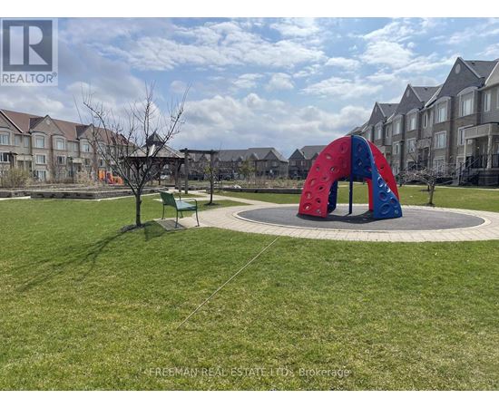 A playground with a red and blue slide in the middle of a grassy area.
