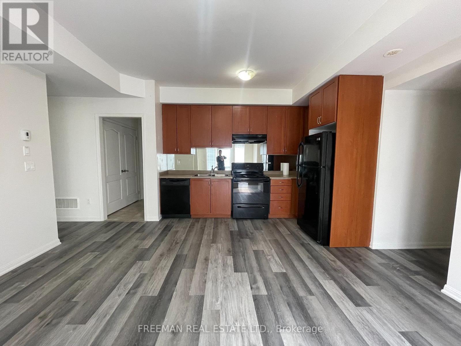 A kitchen with wooden cabinets and a black fridge.