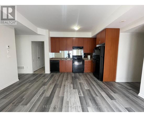 A kitchen with wooden cabinets and a black fridge.