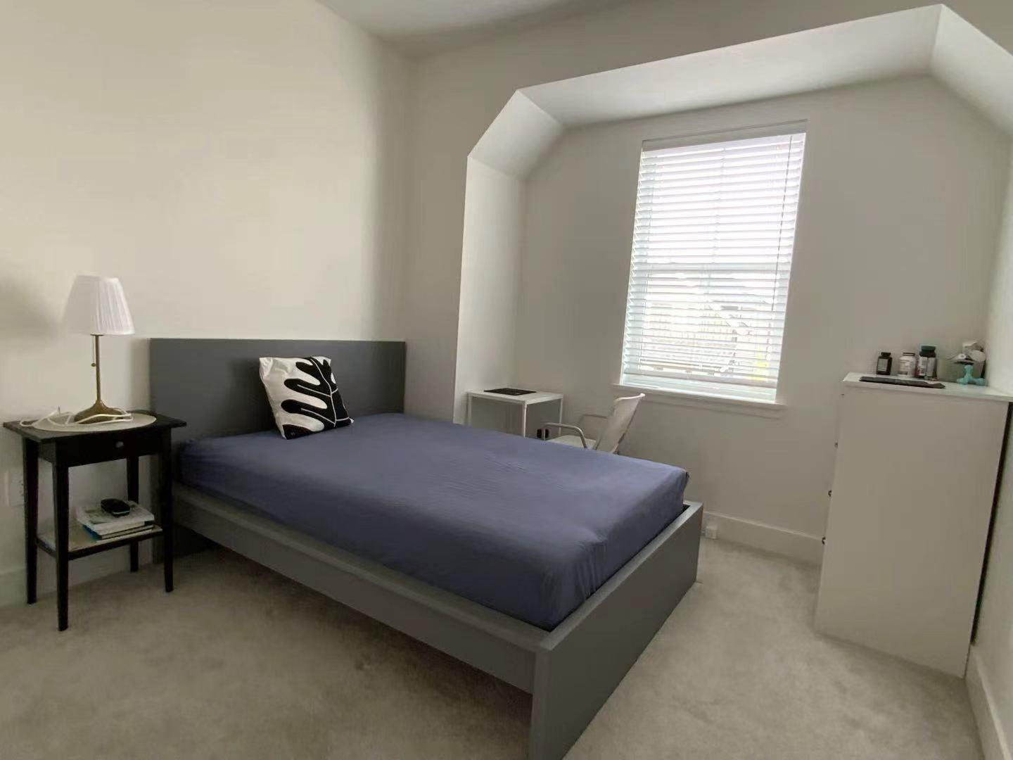 A bedroom with a bed, nightstand, and window.