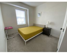A bedroom with a bed, nightstand, and window.