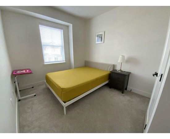 A bedroom with a bed, nightstand, and window.