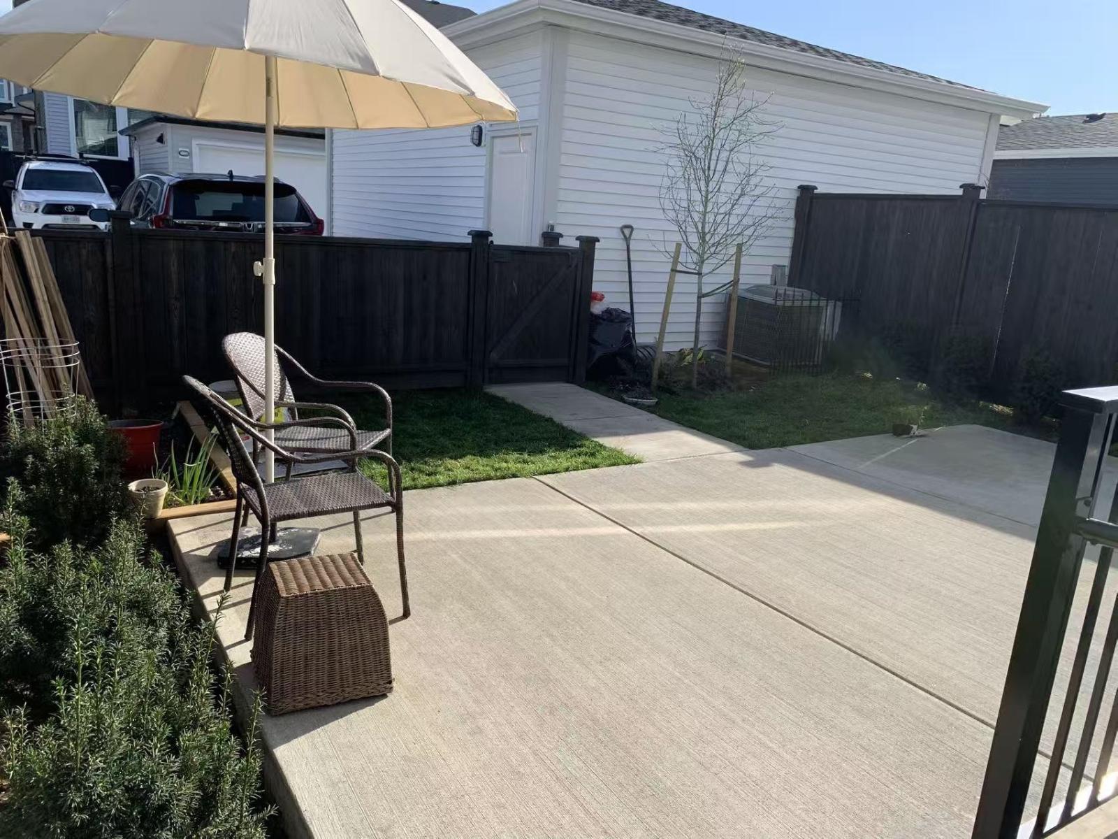A patio with a chair and umbrella is surrounded by a fence.