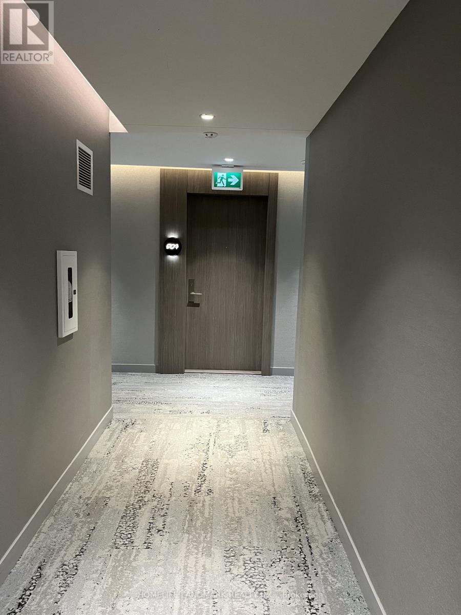 A hallway with a carpeted floor and a wooden door at the end.
