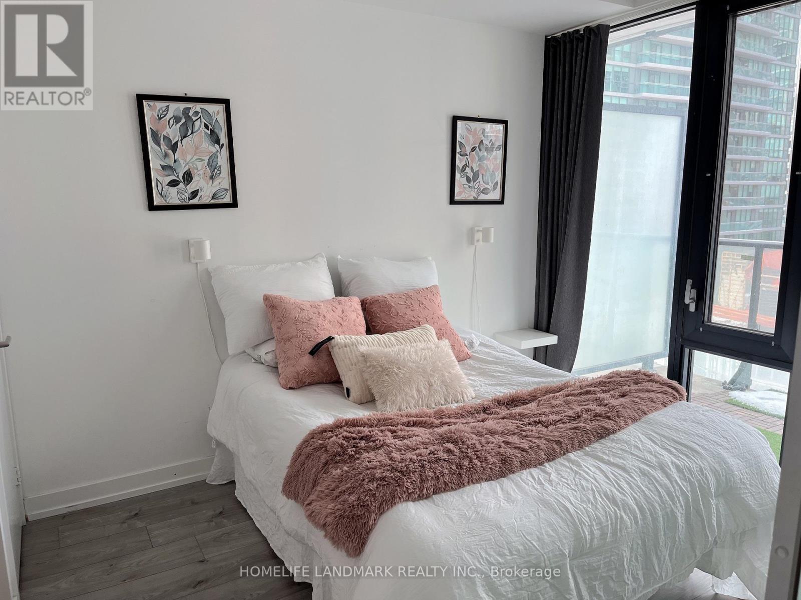 A bedroom with a white bed and a window with black curtains.