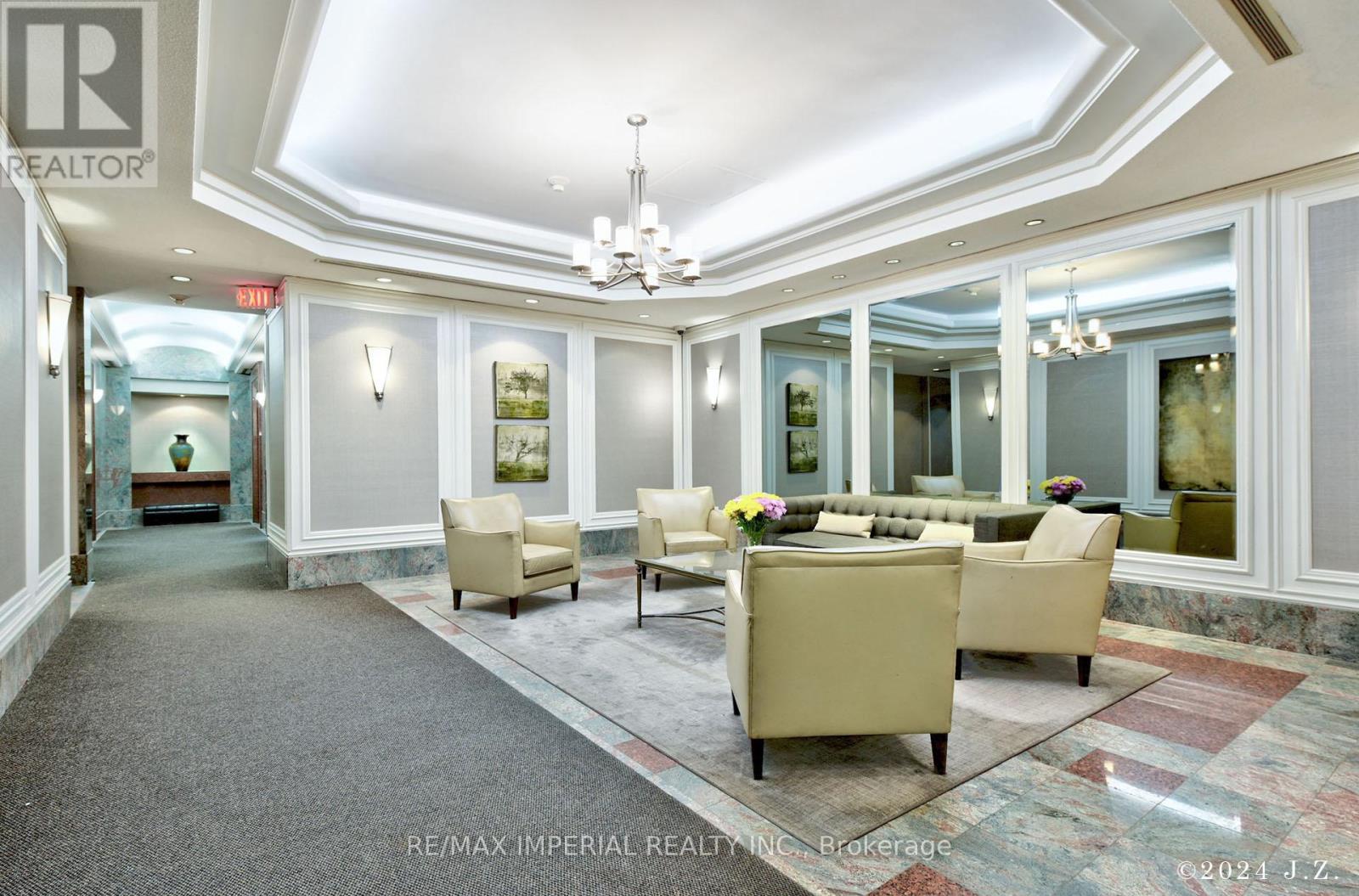 A spacious living room with a large sofa set and a chandelier.