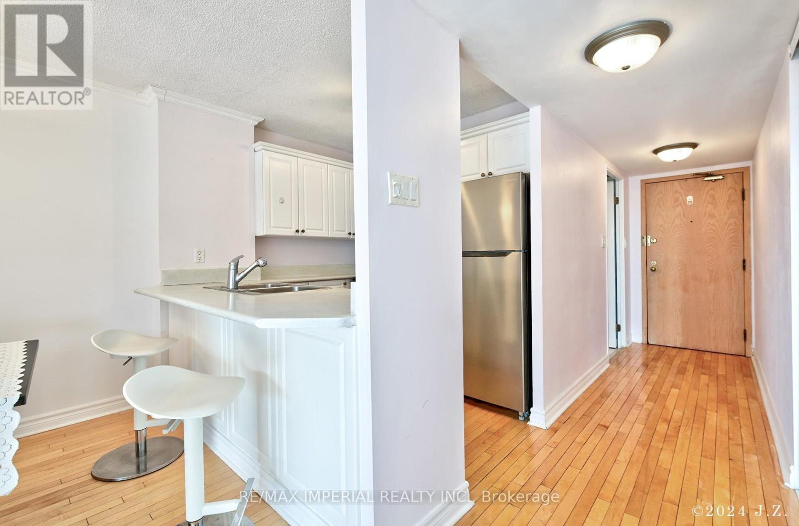 A kitchen with white cabinets and a stainless steel refrigerator.