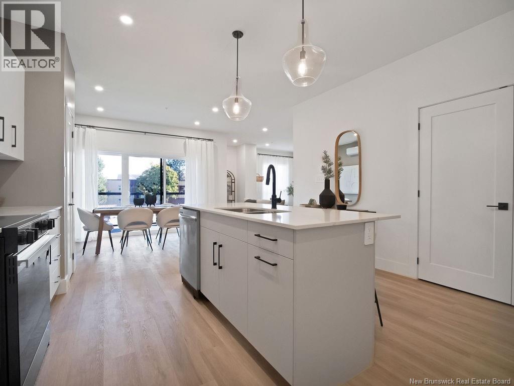 A modern kitchen with white cabinets and a wooden floor.