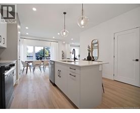 A modern kitchen with white cabinets and a wooden floor.
