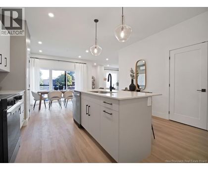 A modern kitchen with white cabinets and a wooden floor.