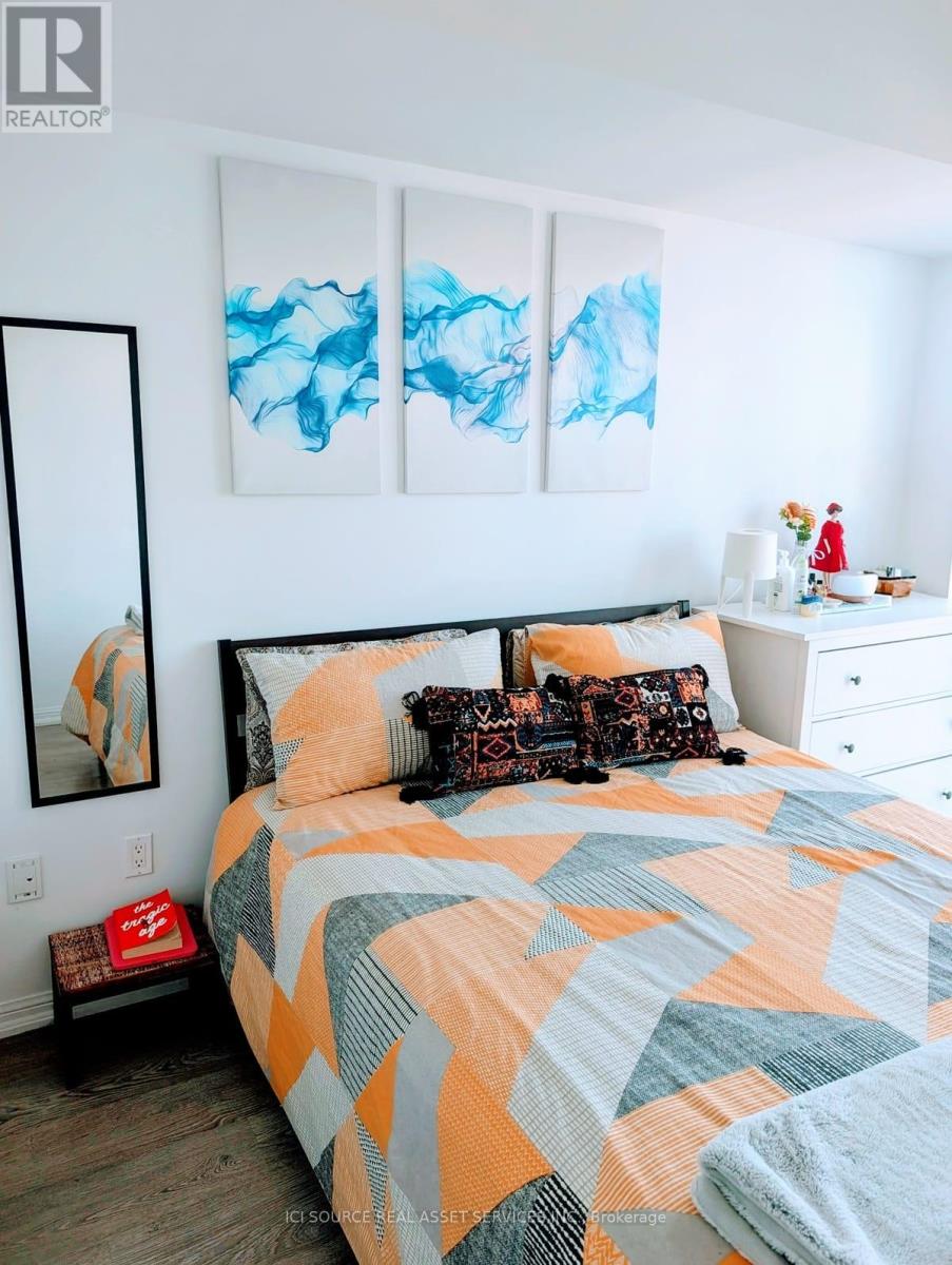A bedroom with a bed, a nightstand, a mirror, and a painting on the wall.