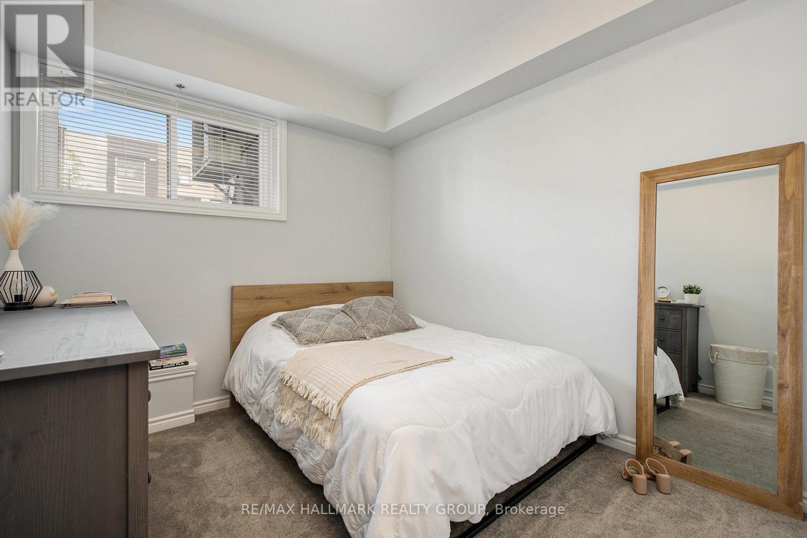 A bedroom with a bed, nightstand, and a mirror.