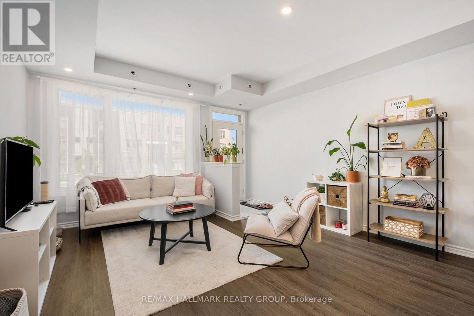A living room with a white sofa, a black coffee table, and a TV.