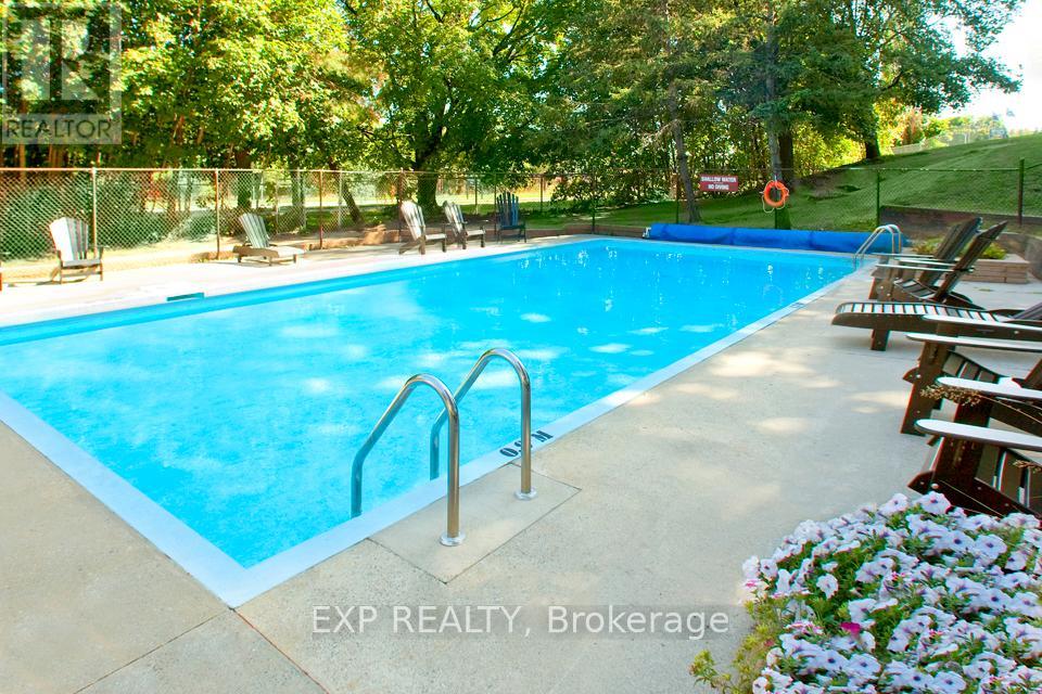 A pool with a metal ladder and chairs around it.