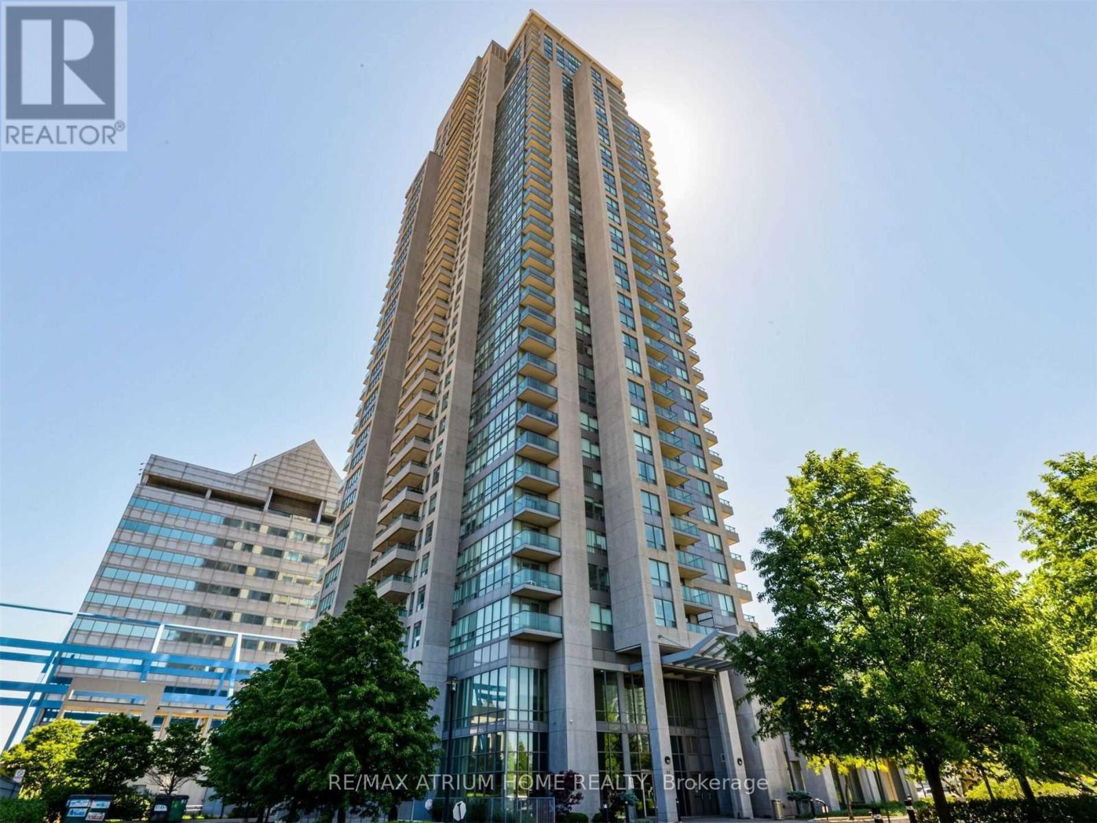 A tall building with a glass facade stands in front of a blue sky.