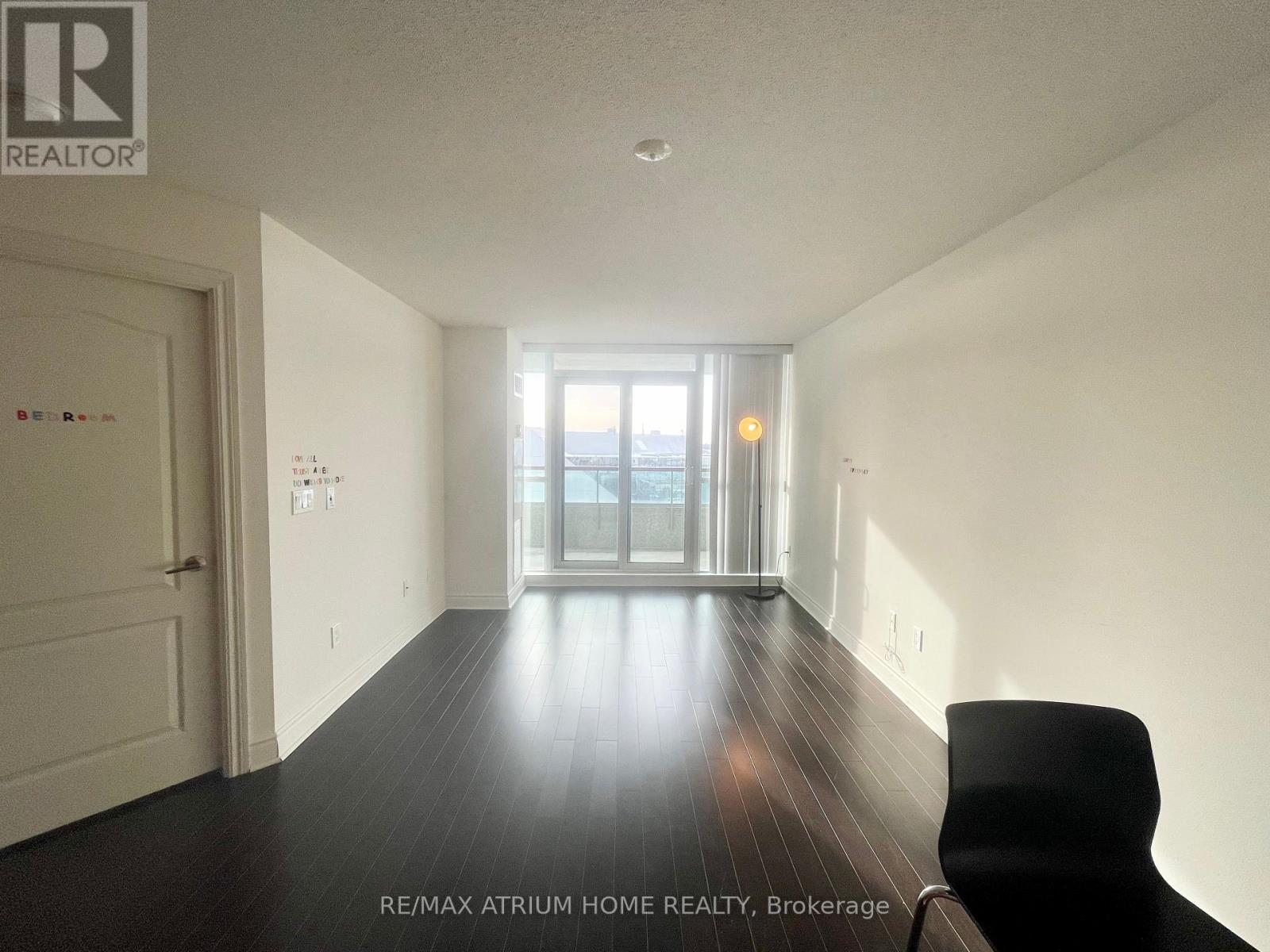 A spacious room with a black chair and a view of the outside through the glass door.