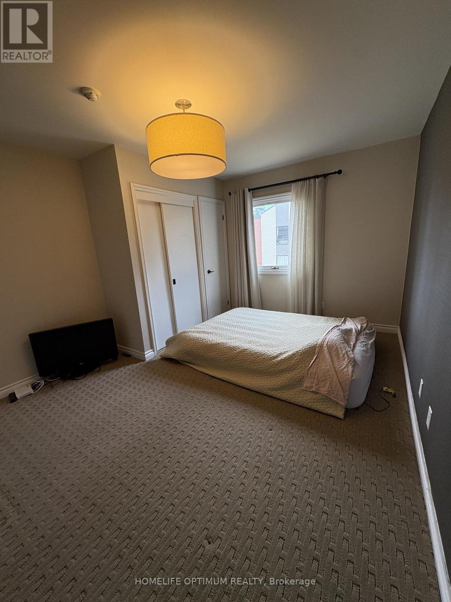 A bedroom with a bed covered in a white sheet and a yellow lamp hanging from the ceiling.