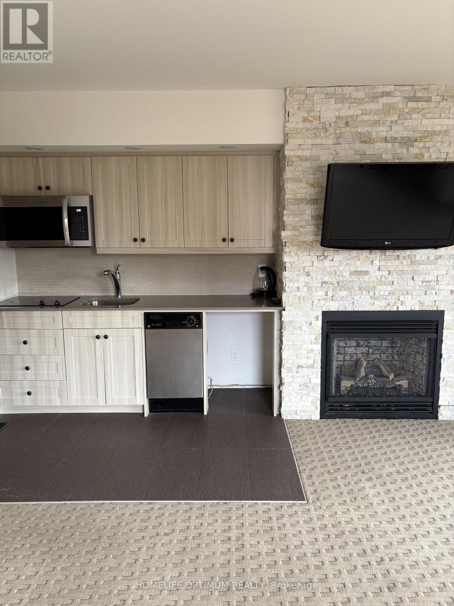 A modern kitchen with a stone fireplace and a flat screen TV mounted above it.