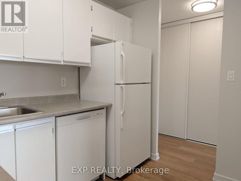 A kitchen with white cabinets and a white refrigerator.