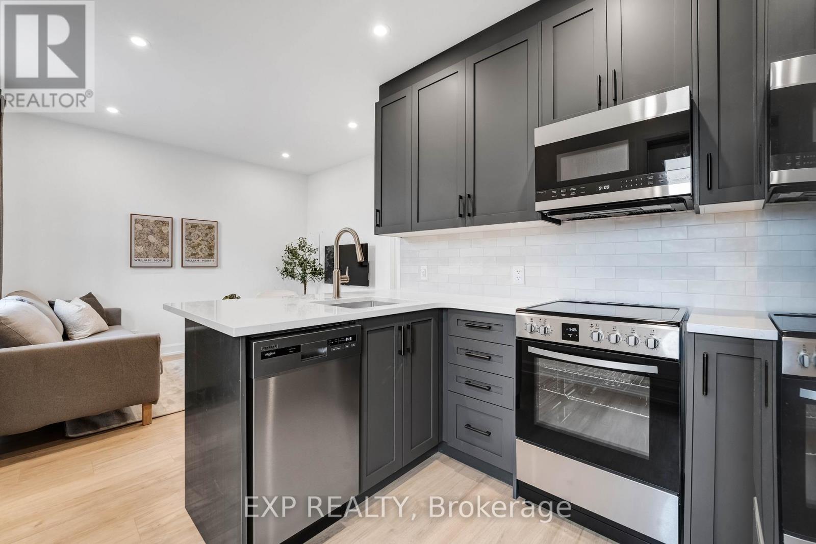 A modern kitchen with black cabinets and stainless steel appliances.