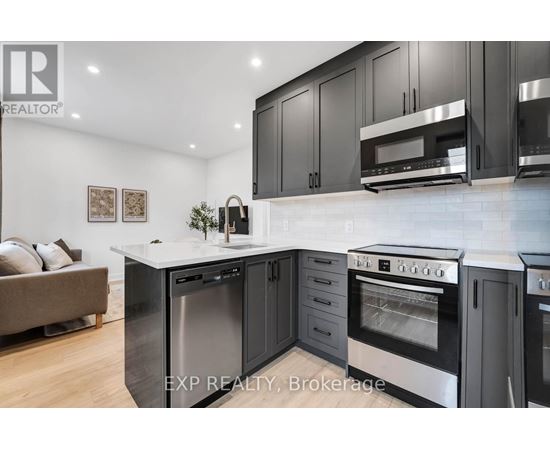 A modern kitchen with black cabinets and stainless steel appliances.