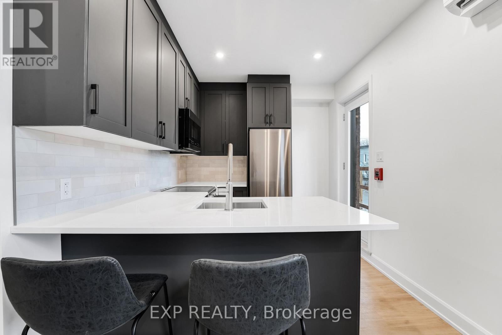 A modern kitchen with a white countertop and dark cabinets.