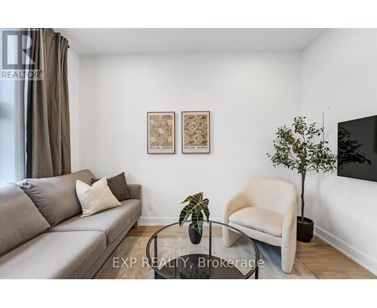 A living room with a grey couch, a white armchair, and a small tree on a glass table.