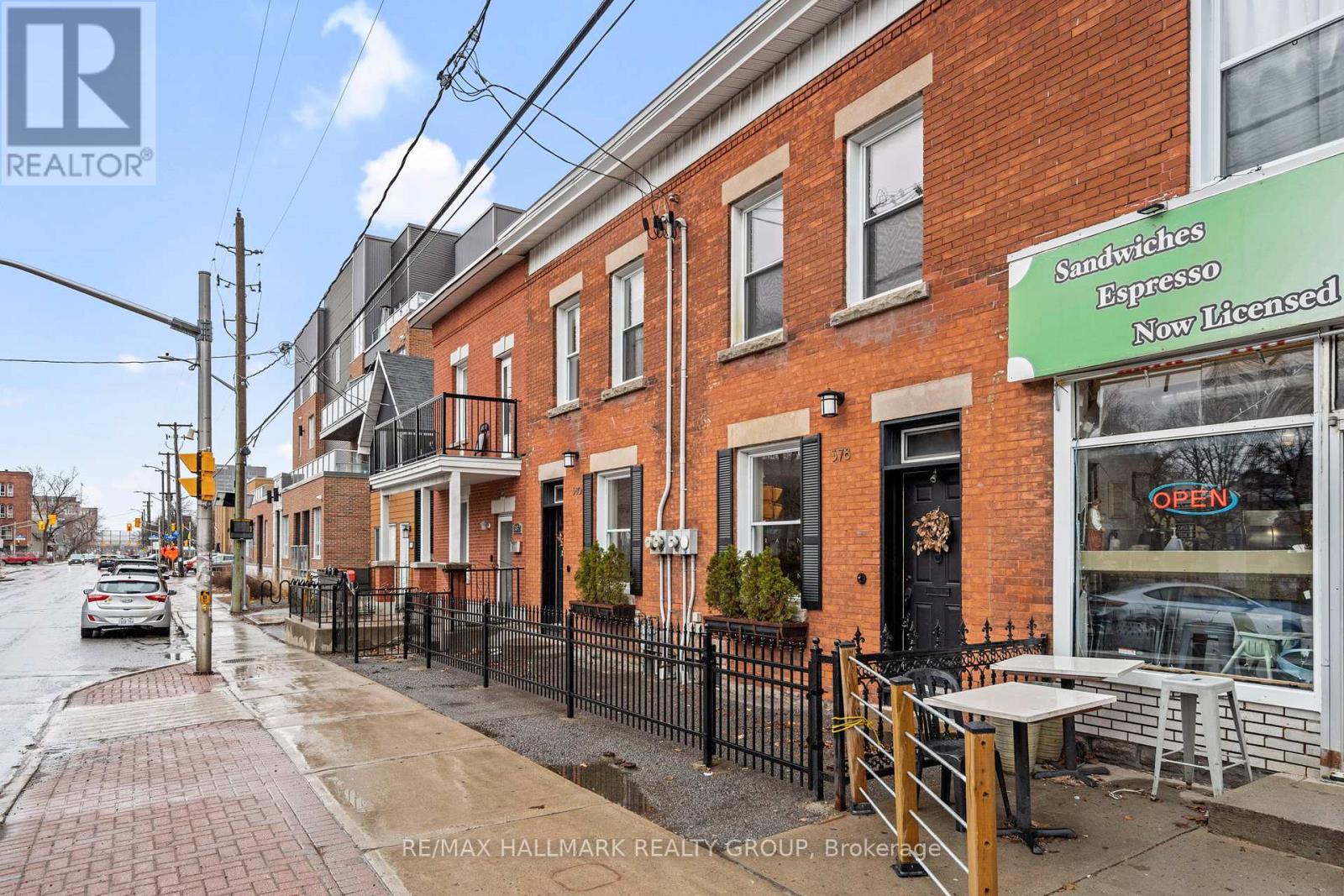 A street view of a row of houses with a sign for Sandwiches and Espresso.