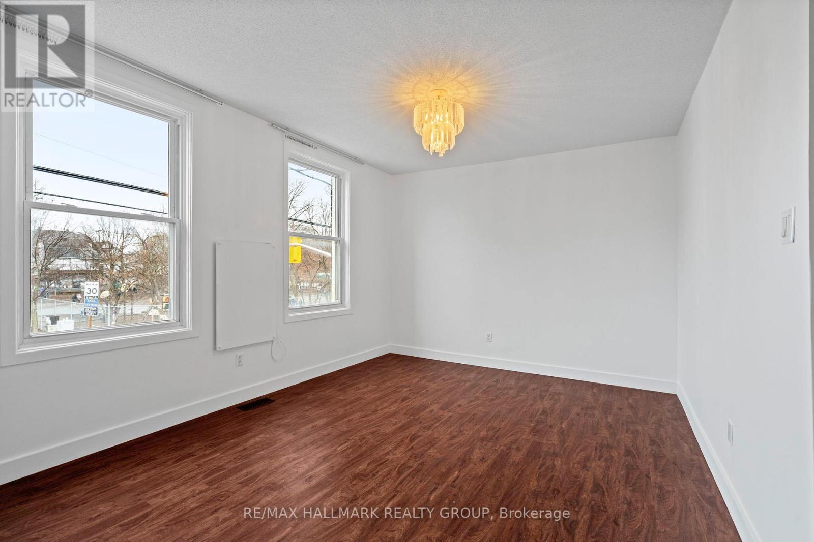 A room with a wooden floor and a chandelier hanging from the ceiling.