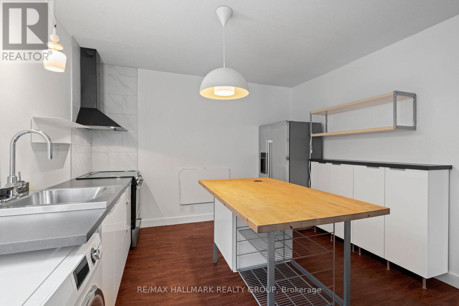 A kitchen with a wooden table and stainless steel appliances.