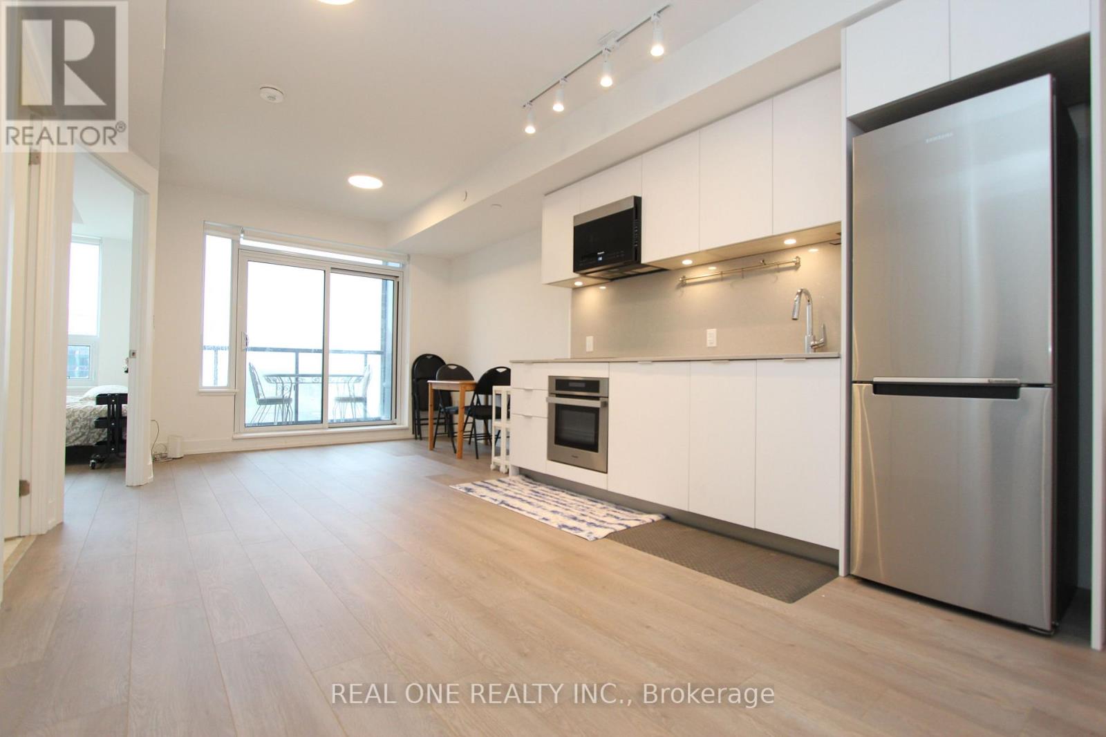 A modern kitchen with white cabinets and a stainless steel refrigerator.