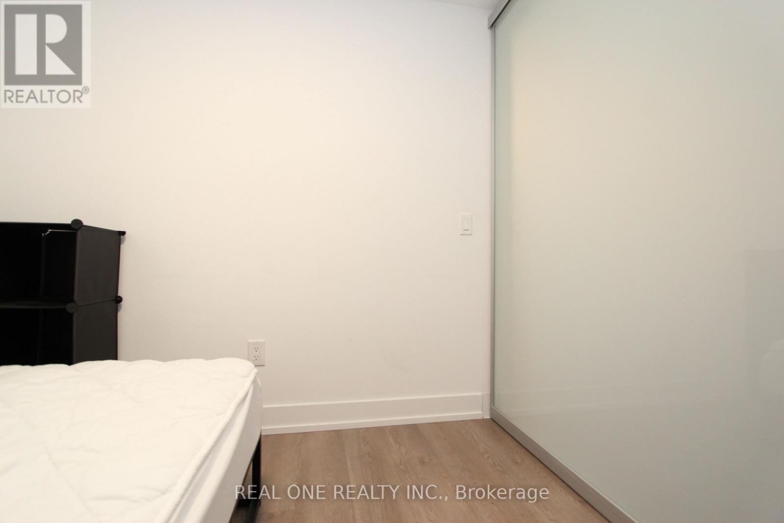 A bedroom with a bed and a black bookshelf.