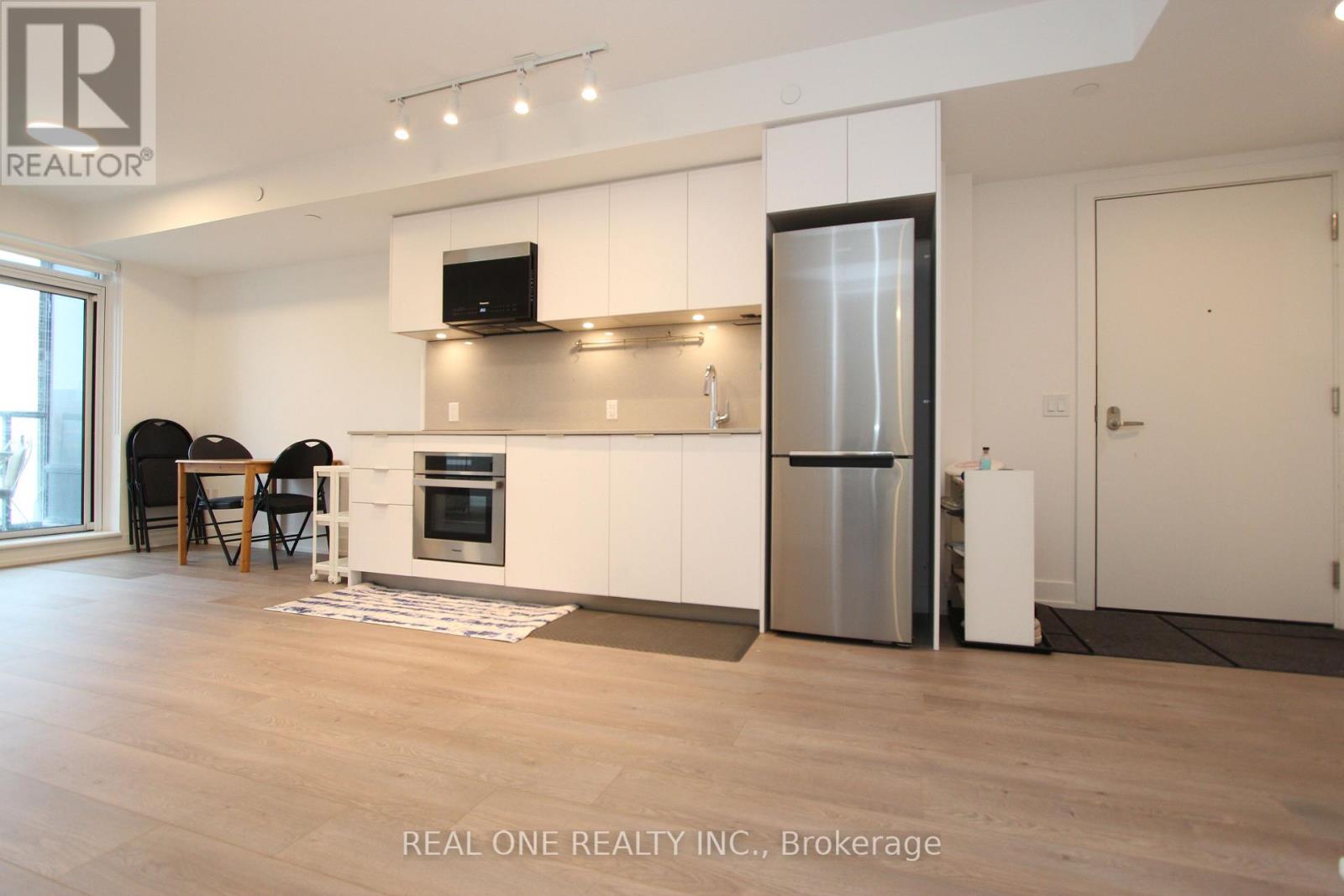 A modern kitchen with white cabinets and a stainless steel refrigerator.