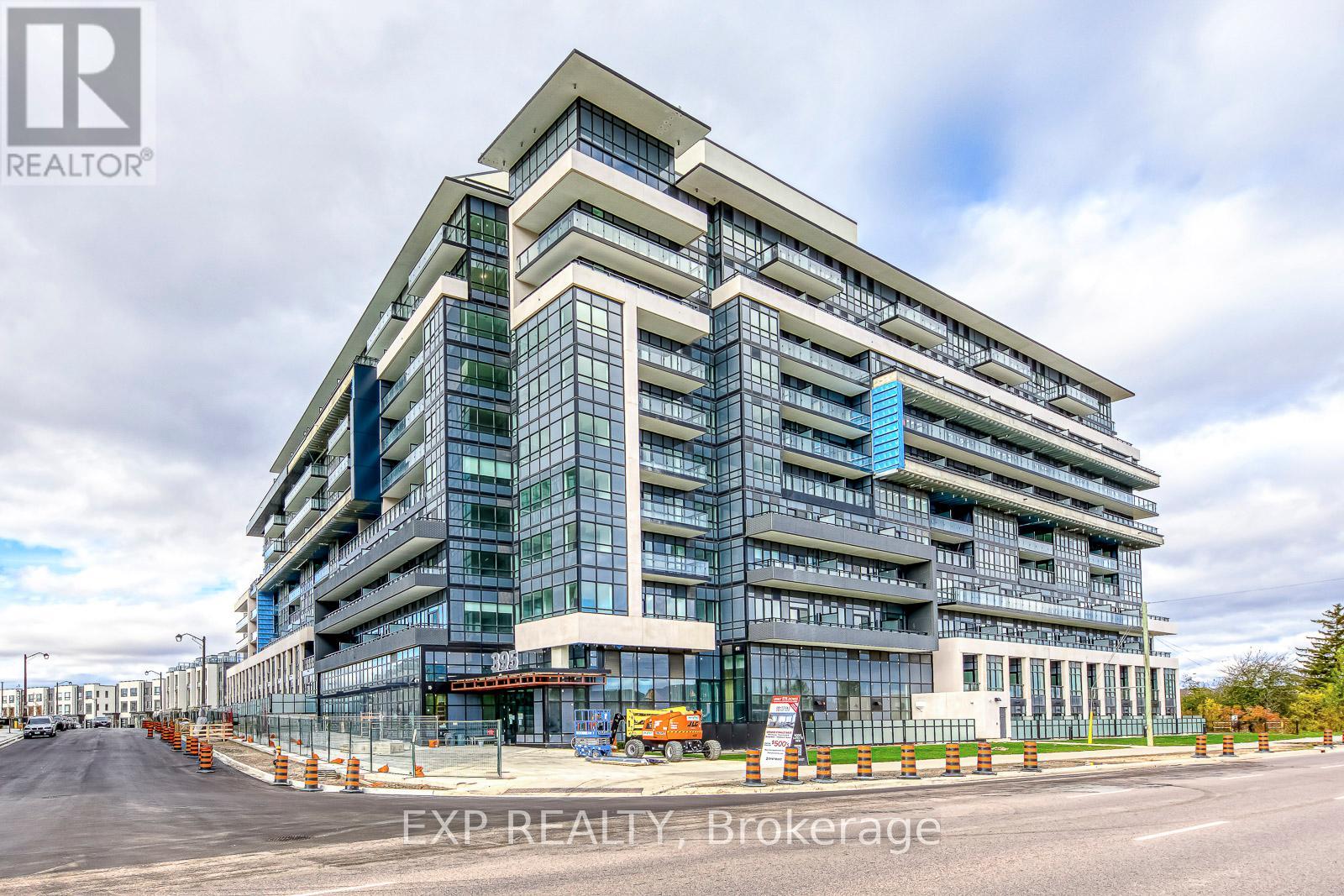 A modern multi-story building with a glass facade and a blue sky in the background.