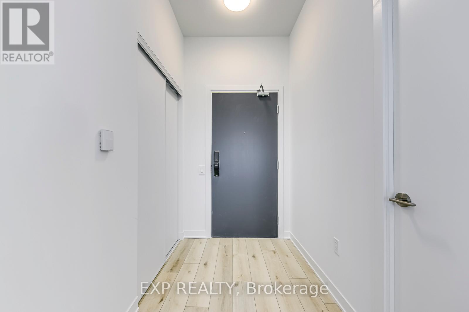 A hallway with a door on the right and a light switch on the wall.
