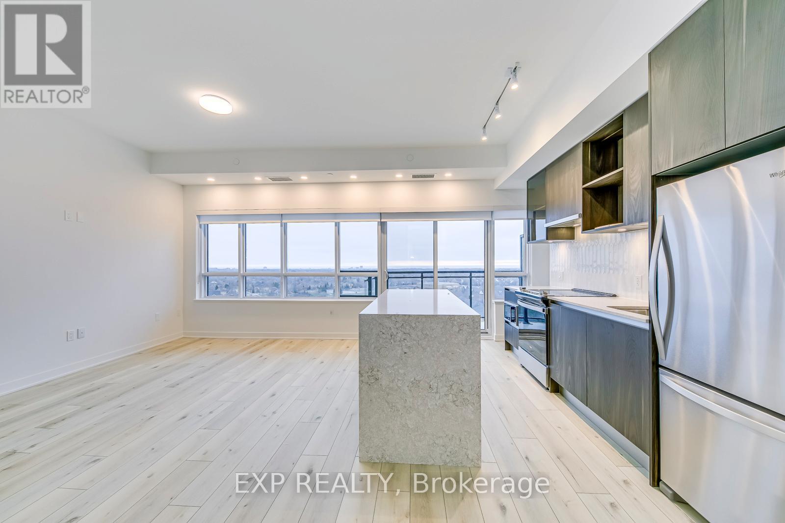 A kitchen with stainless steel appliances and wooden flooring.