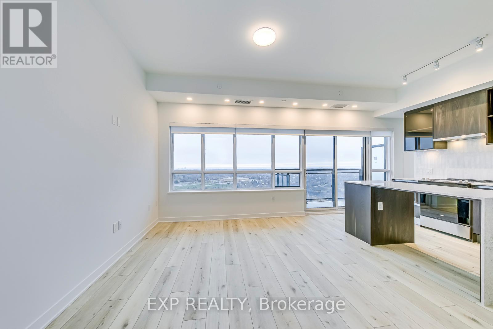 A spacious room with wooden flooring and a large window overlooking a cityscape.