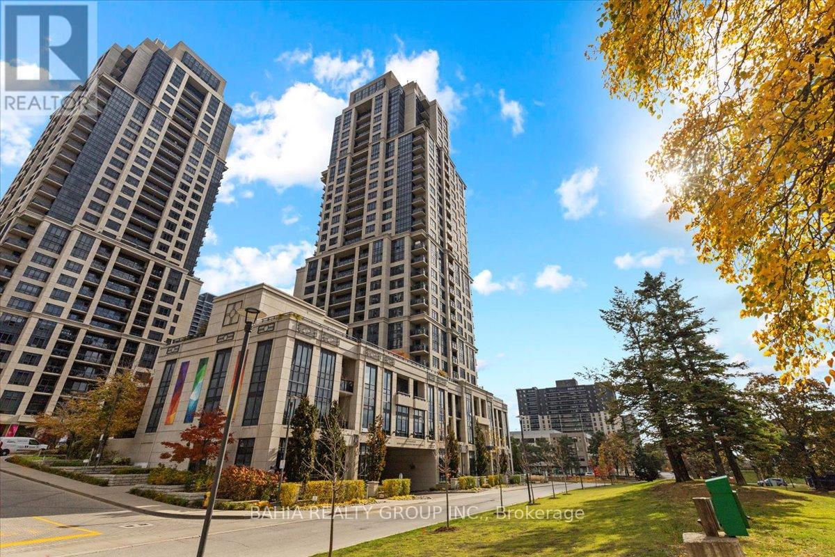 Two tall buildings are in the background of a tree with green leaves.