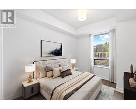 A well-lit bedroom with a large bed and a painting on the wall.