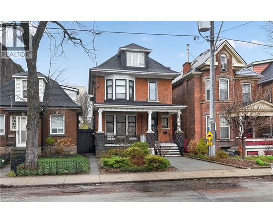 A large red brick house with a black door and a small porch.