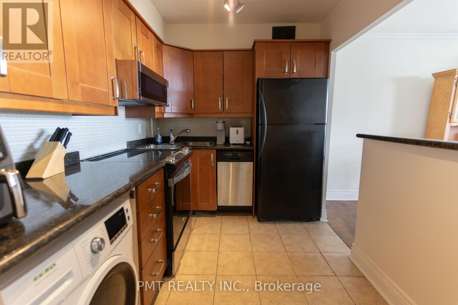 A kitchen with wooden cabinets and a black refrigerator.