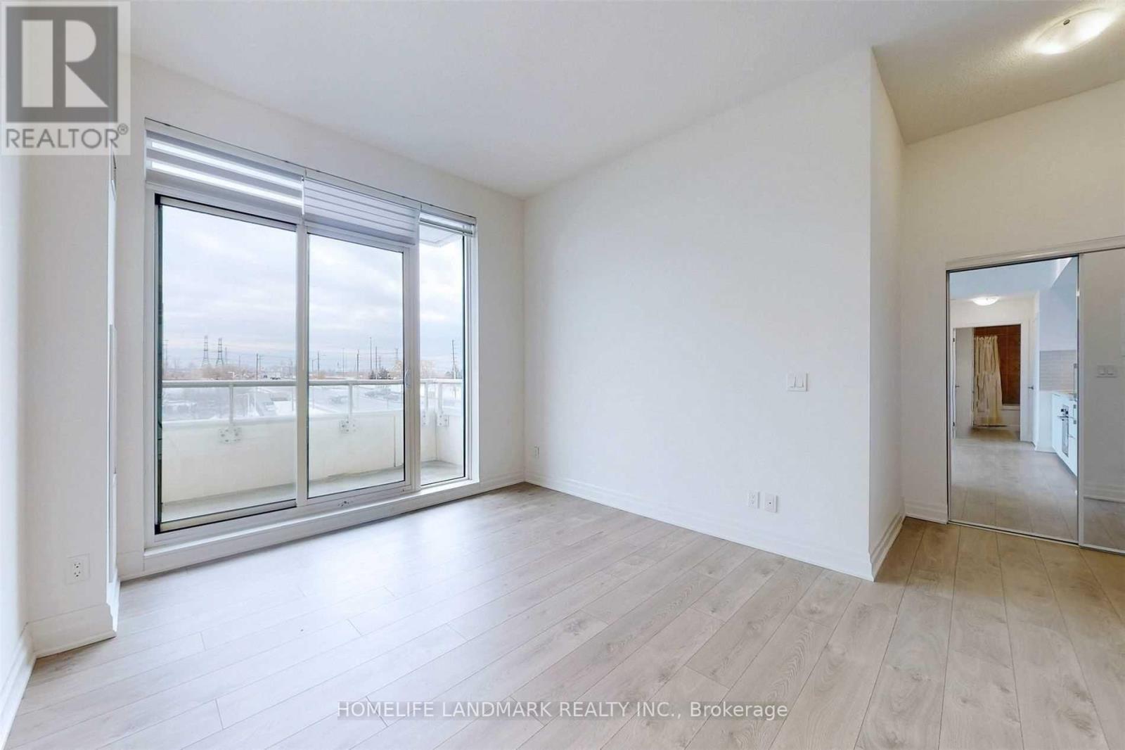 A spacious room with a large window and a door leading to another room.