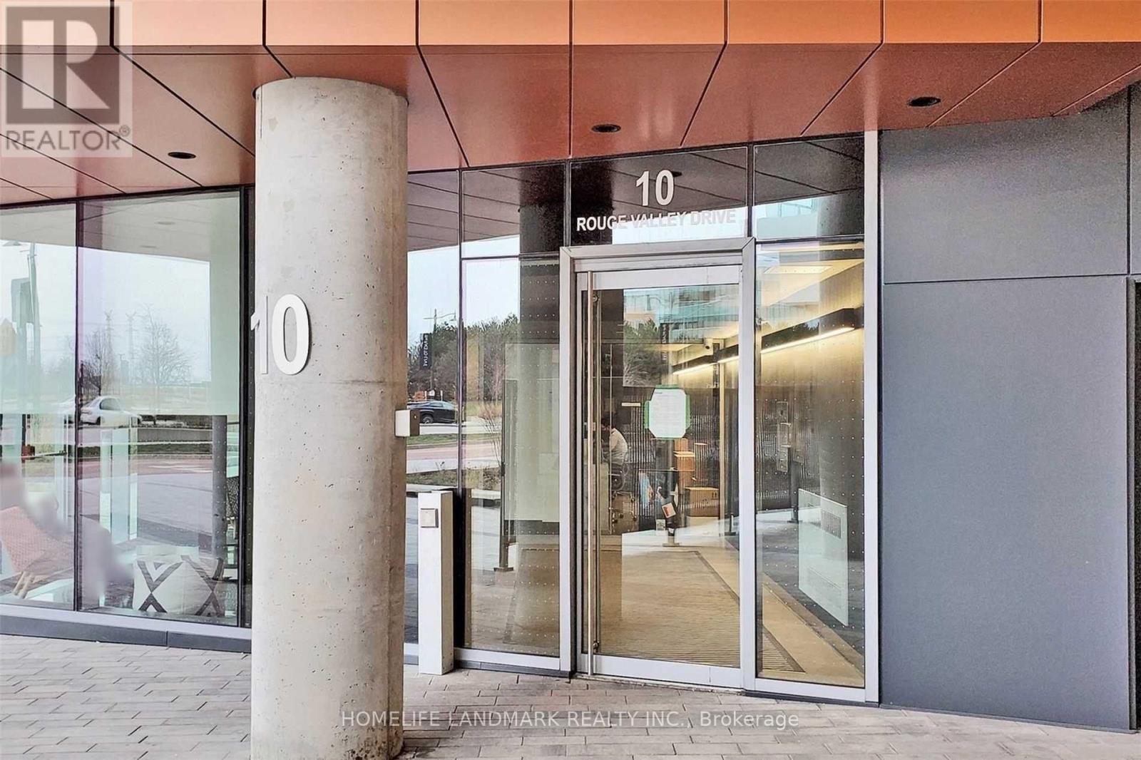 The image shows the front of a building with a glass door and a column with the number 10 on it.