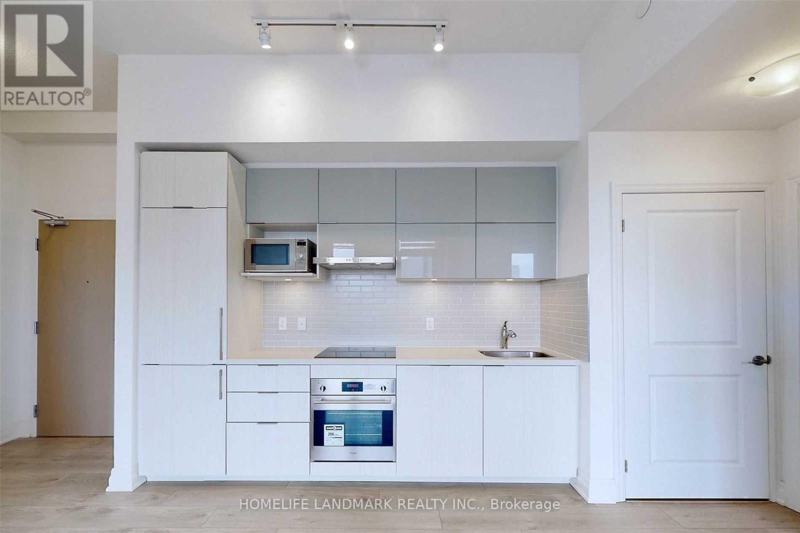 A white kitchen with a sink and a stove top oven.