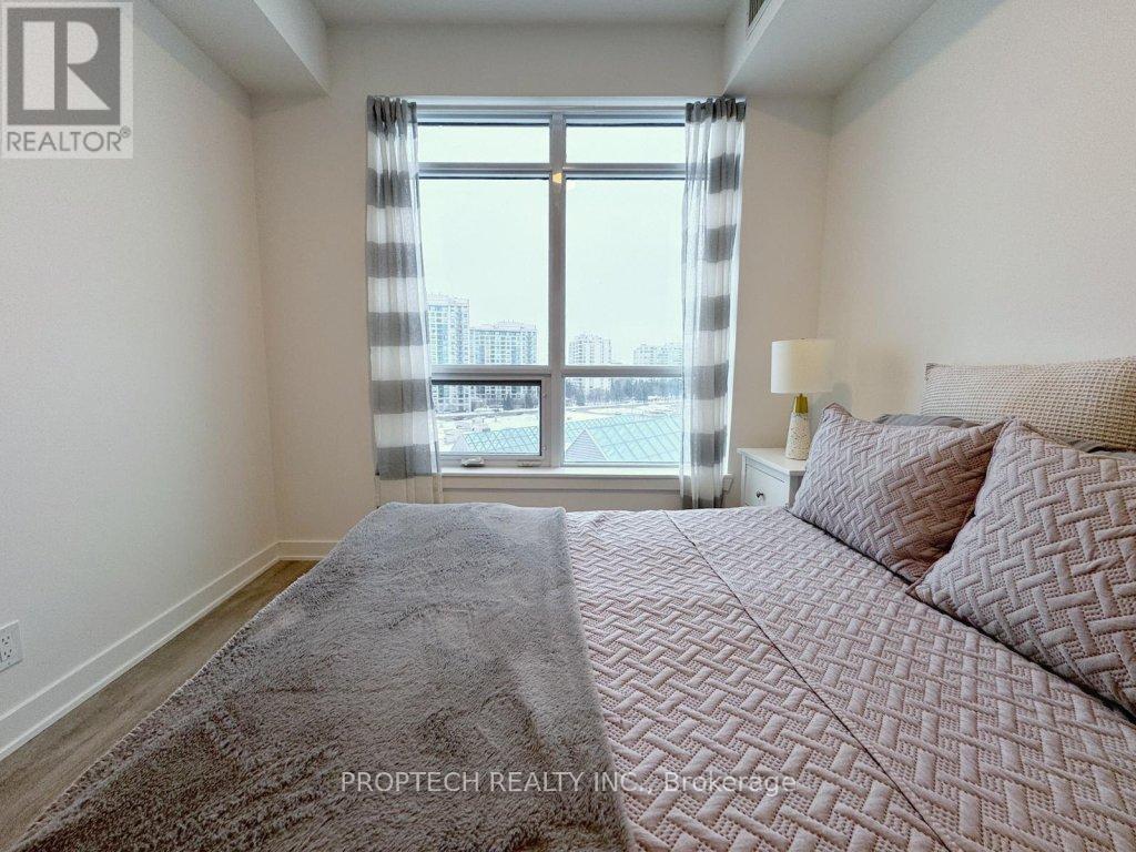 A bedroom with a large bed and a window overlooking a cityscape.
