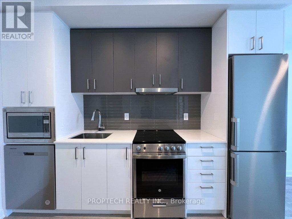 A modern kitchen with a stainless steel refrigerator and a black stove top.