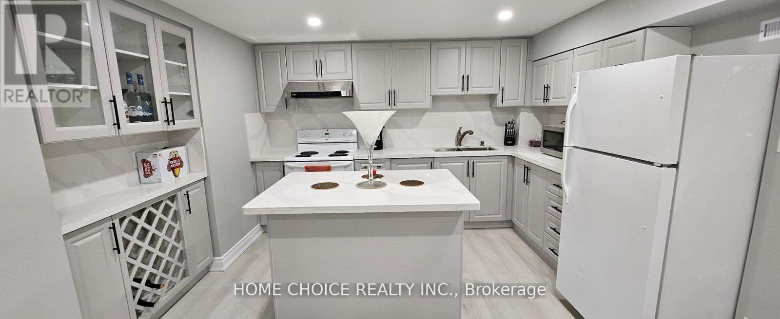 A white kitchen with a refrigerator, sink, and stove.